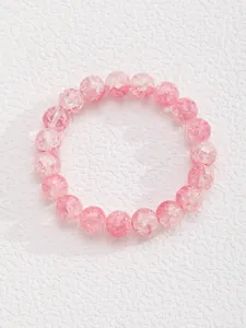 Detalle de pulsera de cuentas de cristal rosa con textura agrietada y acabado pulido suave