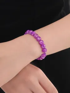 Detalle de pulsera de cuentas de vidrio violeta con textura craquelada en la muñeca