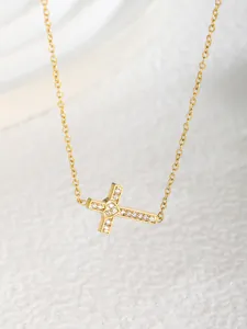 Makroaufnahme der goldenen Kreuzkette mit Zirkonia-Besatz und kleinem Herzdetail