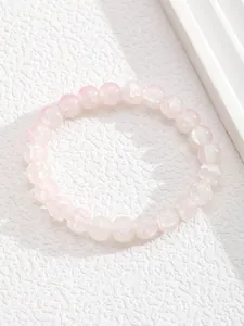 Primer plano de pulsera de cuentas de cuarzo rosa pulido con texturas naturales de piedra