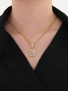 Gros plan du pendentif lettre B dorée avec zircons brillants porté par un modèle