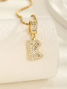 Détail macro du pendentif lettre K dorée avec cristaux de zircone cubique scintillants
