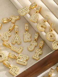 Vue macro de pendentifs alphabet dorés sertis de zircons sur un plateau velours