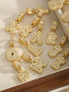 Détail de pendentifs lettres dorés sertis de zircons brillants sur un plateau en bois