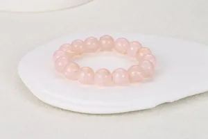 Detalle de cuentas redondas de vidrio rosa translúcido en una pulsera elástica con bandeja