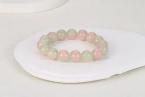 Detalle de cuentas de vidrio translúcido en rosa claro y verde sobre un soporte minimalista