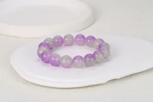 Primer plano macro de cuentas de piedras preciosas moradas y grises en pulsera elástica