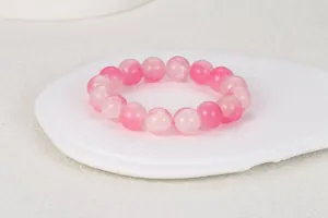 Detalle macro de pulsera de cuentas rosas redondas con textura sobre bandeja cerámica