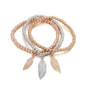 Dreiteiliges Perlenarmband-Set in Roségold und Silber mit Blattanhängern auf weißem Grund