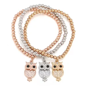 Detailansicht von drei Perlenarmbändern mit Eulenanhängern in Gold, Silber und Roségold