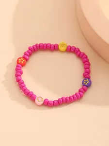 Detalle de una pulsera de cuentas coloridas con estrellas y flores sobre fondo arena