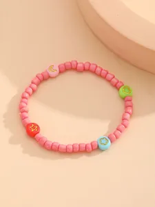 Detalle de pulsera de cuentas rosas con dijes de luna, estrella, flor y corazón