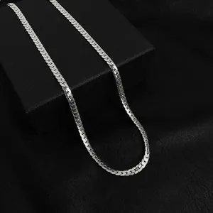 Macro shot of silver-toned stainless steel Cuban link chain on a black textured box