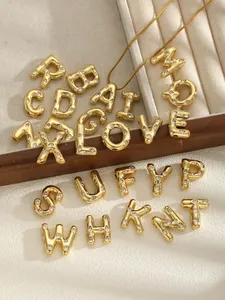 Detailed macro view of gold-plated stainless steel alphabet pendants with shiny zircon stones