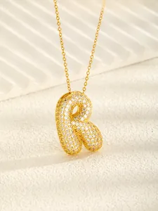 Close-up of a 3D bubble letter R necklace pendant gold plated with sparkling cubic zirconia