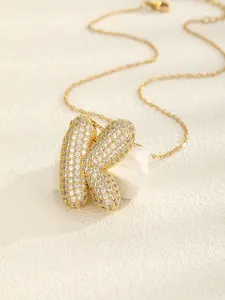 Close-up of golden necklace with 3D letter K pendant paved in sparkling white zircons