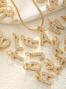 Détail des pendentifs lettres en or sertis de pierres en zircone scintillantes