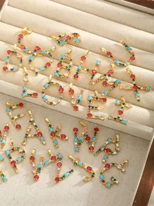 Macro shot of gold-plated alphabet pendants with multi-color zircon stones in a jewelry box
