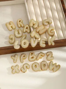 Macro detail of 3D gold bubble letter pendants with sparkling zircon stone pavé