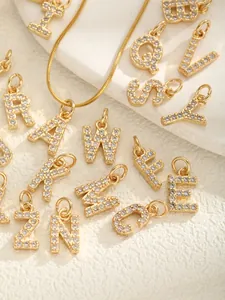 Détail macro de pendentifs lettres dorés sertis de micro-pavé de zircons blancs