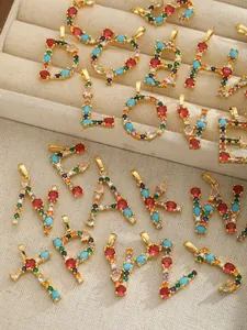 Close-up of gold-plated alphabet pendants with vibrant colorful cubic zirconia inlay