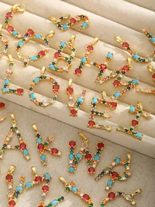 Macro view of gold-plated alphabet pendants with multicolored zircon gemstones