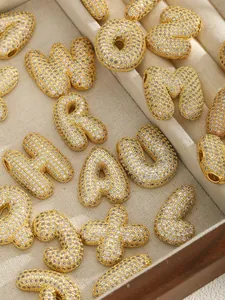 Macro view of gold-plated puffy bubble letters with micro-paved cubic zirconia