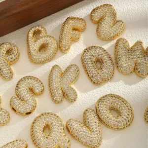 Golden chunky alphabet pendants with cubic zirconia inlay on textured background