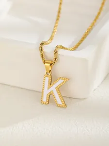 Dettaglio del ciondolo lettera K dorata con smalto bianco e bordo decorato