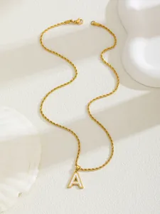 Dettaglio di una collana dorata con pendente a lettera A in smalto bianco su pietra decor