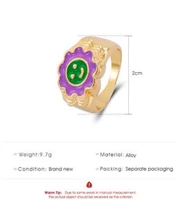 Detalle del anillo de aleación dorada de 2cm con flor púrpura y cara sonriente verde
