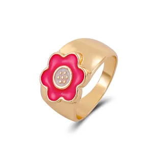Detalle de anillo de flor dorada con esmalte rosa y banda ancha para mujer