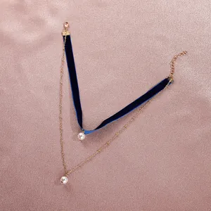 Λεπτομέρεια από βελούδινο τσόκερ με διπλή χρυσή αλυσίδα και λευκά μαργαριταρένια μενταγιόν