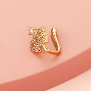 Detail of a gold S-shaped nose clip featuring sparkling cubic zirconia on pink background