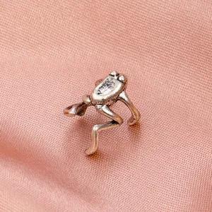 Vintage punk silver frog ear cuff with aged metal texture on pink silk fabric background