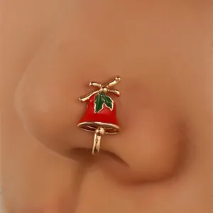 Close-up of Christmas bell faux nose ring with red enamel and green holly detail