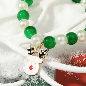 Macro detail of Christmas beaded bracelet with green pearls and reindeer charm