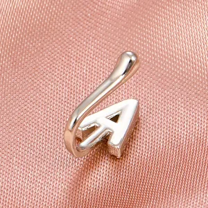 Macro detail of silver U-shaped nose cuff with a polished letter A on pink silk fabric