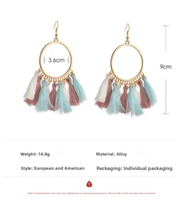 Detail view of colorful cotton fringe tassels on golden metal fan-shaped earrings
