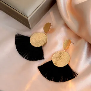 Detailed macro view of bohemian black fan tassel earrings with gold hammered metal discs