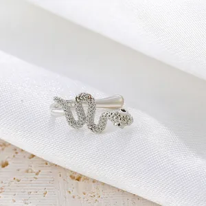Macro detail of silver snake-shaped ear cuff showing realistic scale texture and metallic curves