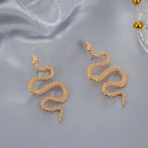 Pendientes de serpiente dorados con textura de escamas sobre un fondo de raso lujoso