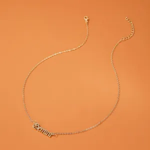 Gros plan du pendentif zodiaque Gemini doré avec fine chaîne sur fond orange clair