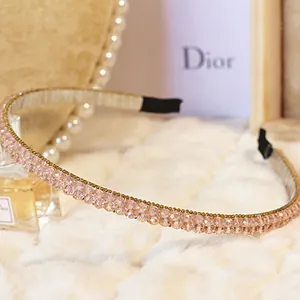 Detail shot of pink crystal beaded headband on white plush background with elegant props