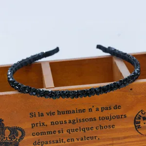 Close-up of black beaded headband with faceted crystals on a vintage wooden box