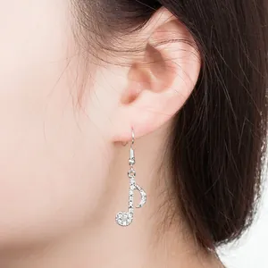 Elegante silberne Musiknoten-Ohrhänger mit funkelnden Strasssteinen an einem Modell
