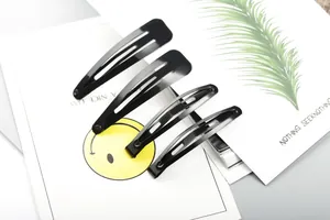 Set of four black metal drop-shaped snap hair clips arranged on a minimalist white card