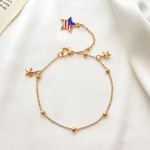 Detailansicht goldene Stern-Fußkette mit US-Flaggen-Emaille und Perlen auf weißer Seide