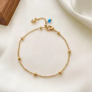 Elegantes goldenes Perlen-Fußkettchen mit Sternanhänger und blauer Perle auf weißer Seide