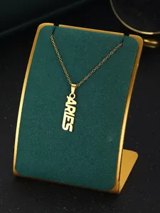 Detailed close-up of Aries gold pendant necklace on green velvet jewelry display stand